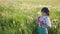 portrait of a five year old boy in a hat stands on a field of dandelions and shoots soap bubbles from a toy gun at