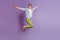 Portrait of flying positive active guy jump have fun on violet background