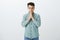 Portrait of focused calm attractive guy in casual outfit, holding hands in pray over mouth, closing eyes and praying or
