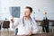 Portrait of focused male doctor wearing white uniform examining brain computerized tomography scan sitting at desk in