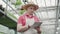 Portrait of focused man standing in greenhouse and typing on tablet. Front view of confident professional Caucasian