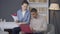 Portrait of focused serious young African American man typing on laptop keyboard as Caucasian woman talking analyzing