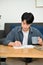 Portrait, Focused young Asian male college student sipping coffee while doing homework