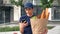 Portrait food delivery woman courier uses smartphone holds paper bag in hand