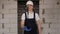 Portrait of a foreman in overalls and a white helmet with a hammer in his hands.