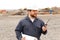 Portrait of foreman standing on construction site, talking by VHF walkie talkie and holding blueprints.