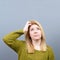 Portrait of forgetful young woman against gray background