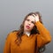 Portrait of forgetful young woman against gray background