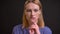 Portrait of formally-dressed woman thoughtfully touching her chin and getting an insight on black background.