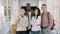 Portrait of four smiling positive attractive multi-ethnic male and female students standing in spacious white corridor