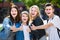 Portrait of four teenagers standing and holding thumbs up together outdoors