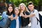 Portrait of four teenagers standing and holding thumbs up together outdoors