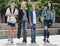 Portrait of four teenagers walking together in town on summer da