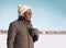 Portrait free young african man enjoying drinking coffee over blue sky in cold winter looking profile