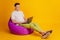 Portrait of freelancer worker guy sit beanbag typing laptop toothy smile on yellow background