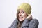 Portrait of freezing young woman with yellow beanie covering head on cold winter weather