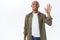 Portrait of friendly african-american male in casual outfit, seeing person in crowd, attract friends attention, waving