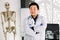 Portrait of friendly Asian Korean doctor man at his office smiling to camera. Young smiling clinician in white coat