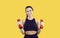 Portrait of friendly beautiful female personal fitness trainer on vivid yellow background.