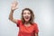 Portrait of friendly blonde girl waving hand and looking at camera. Studio shot, white background.Human emotions concept