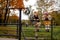 Portrait of friendly cute couple kids boy and girl walking and playing in autumn park. Climb the fence. Kids wearing