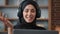 Portrait friendly Islam Arabian Muslim woman distant teacher businesswoman in black hijab smiling lady in headphones