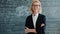 Portrait of friendly lady teacher standing in classroom with arms crossed alone