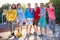 Portrait of friendly team of sportive teenagers holding basketball ball and skateboard