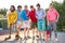 Portrait of friendly team of sportive teenagers holding basketball ball and skateboard