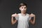 Portrait of friendly teenage boy wearing white t-shirt pointing at his chest. Studio shot against grey background