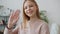 Portrait of friendly teenager waving hand and smiling standing in apartment alone