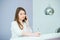 Portrait of friendly young woman talking on phone and making note behind the reception desk. Administrator in the office, clinic,