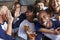 Portrait Of Friends Watching Game In Sports Bar On Screens