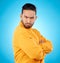 Portrait, frown and asian man with arms crossed in studio angry, frustrated and annoyed on blue background. Conflict