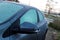 A portrait of a frozen side mirror and side windows of a completely frozen car during winter time. The ice first needs to melt or