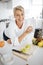 Portrait, fruit salad and apple with an old woman in the kitchen of her home for health, diet or nutrition. Smile, food