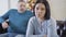 Portrait of frustrated Caucasian brunette woman sitting on couch on Christmas eve and thinking as blurred man sitting at