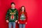 Portrait of frustrated frightened two youth people with brunette wavy hair dislike christmas tree pattern decor jumper