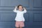 The portrait of a frustrated little girl holds her hands up, wearing a white blouse and red shorts