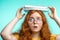 Portrait of frustrated teenage girl carrying book on head  on blue