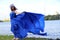 Portrait in full growth on the banks of the river, in a windy warm summer day. woman in a gorgeous long blue dress