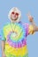 Portrait of funky young man gesturing peace sign against blue background