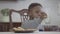 Portrait of funny african american child boy sitting by the table and drinking milk from the glass on the background of