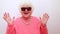 Portrait of funny amazed surprised senior blonde woman in sun glasses and pink sweater on white background having fun