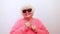 Portrait of funny amazed surprised senior blonde woman in sun glasses and pink sweater on white background having fun