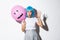 Portrait of funny asian girl trying to scare someone on halloween, wearing blue wig and holding pink balloon with scary