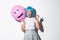 Portrait of funny asian girl trying to scare someone on halloween, wearing blue wig and holding pink balloon with scary