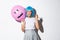 Portrait of funny asian girl trying to scare someone on halloween, wearing blue wig and holding pink balloon with scary