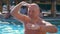 Portrait, funny bald middle-aged man, with a naked torso, something fun sings, dances, by the pool on vacation, in