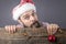 Portrait of a funny bearded man with santa cap holding a red round Christmas ball
